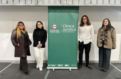 Four people stand in a hallway beside a green banner that reads 'Universidad Andrés Bello' and 'Clínica Jurídica - Sede Santiago'.