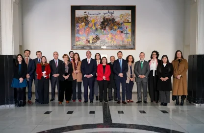 Group of around 20 formally dressed people posing for a photo in a marble hallway, with a colorful mural hanging above them.