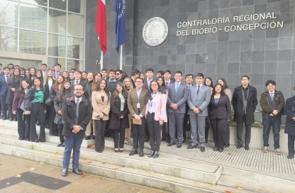 Group of people in formal attire posing on the steps outside the Contraloría Regional del Biobío in Concepción, Chile.