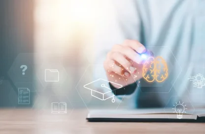 Hand reaches toward a glowing holographic brain icon amid education-themed symbols like a graduation cap and book over a tablet, conveying digital learning and neuroscience.